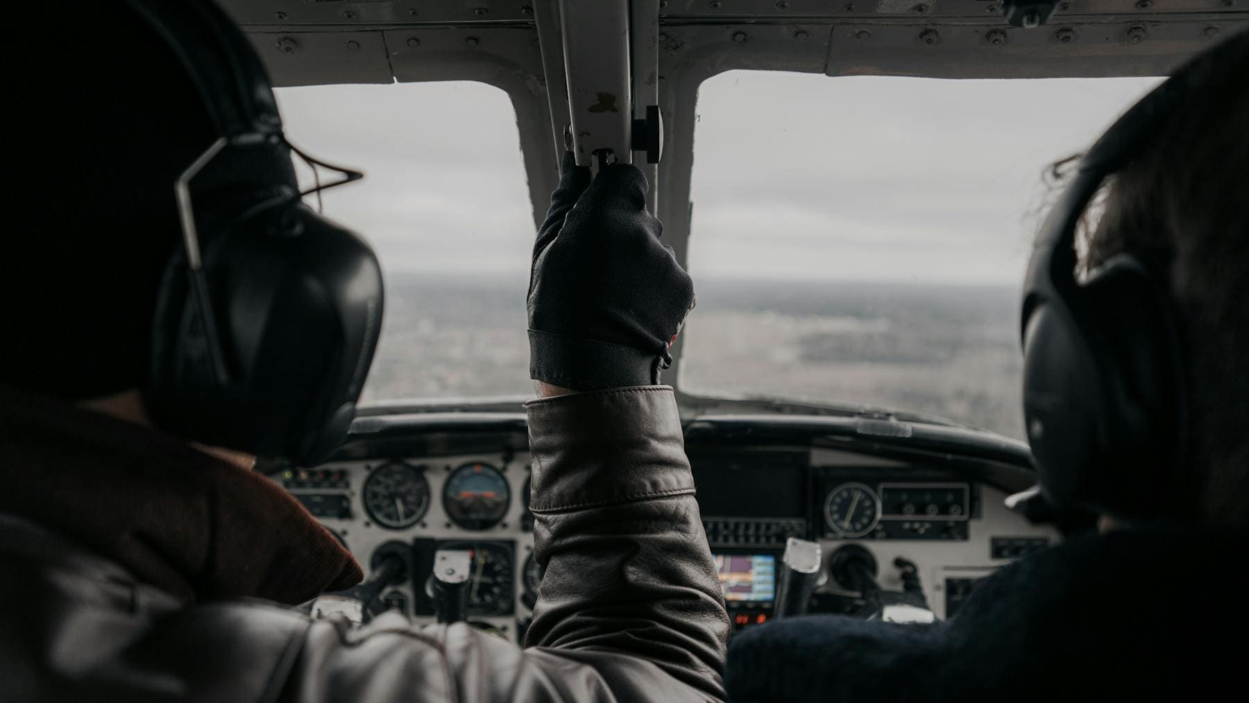 Two pilots operating a small aircraft cockpit during flight training